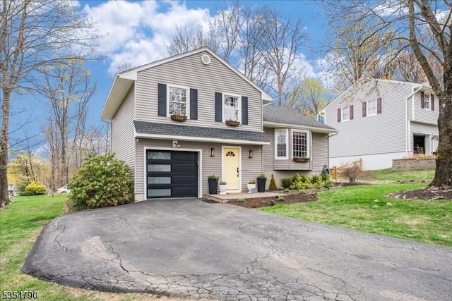 tri-level home with roof with shingles, an attached garage, a front lawn, and aphalt driveway