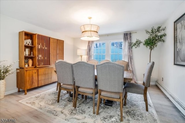 dining space featuring light wood-style floors, baseboards, and a baseboard radiator