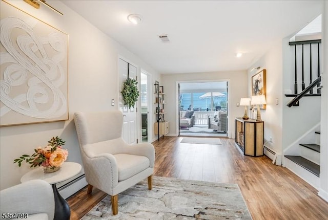 interior space featuring light wood-style floors, a baseboard heating unit, and stairs