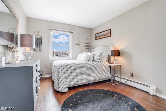 bedroom with wood finished floors, baseboards, and a baseboard heating unit