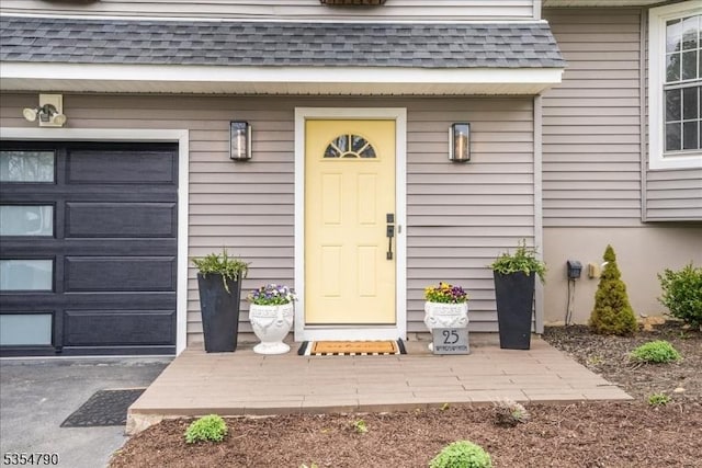 property entrance featuring roof with shingles and a garage
