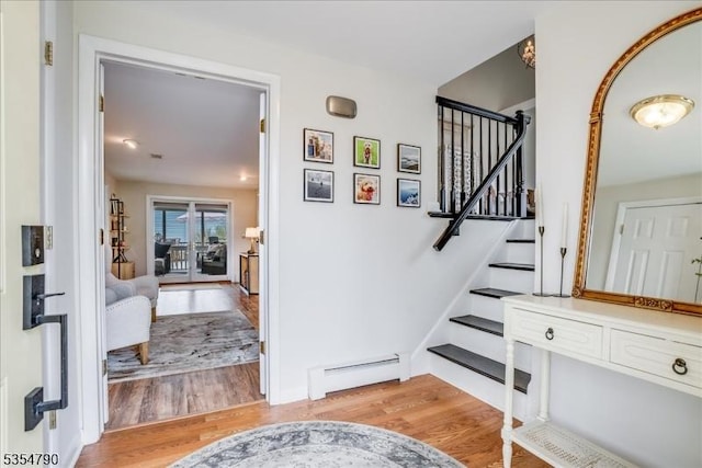 staircase with wood finished floors and baseboard heating
