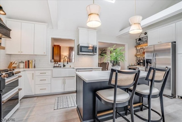 kitchen featuring backsplash, appliances with stainless steel finishes, a sink, light countertops, and white cabinetry