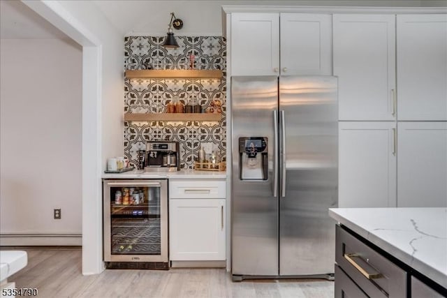 bar with a dry bar, light wood-style floors, beverage cooler, stainless steel refrigerator with ice dispenser, and a baseboard heating unit
