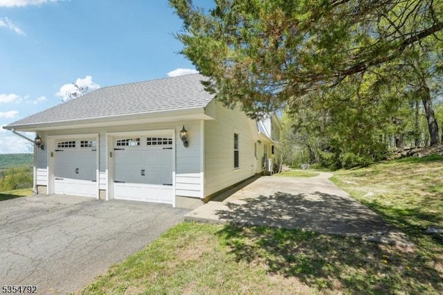 view of side of home featuring a garage and a shingled roof
