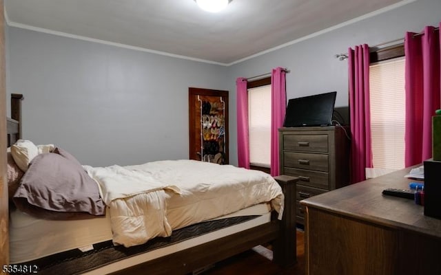 bedroom with ornamental molding and wood finished floors