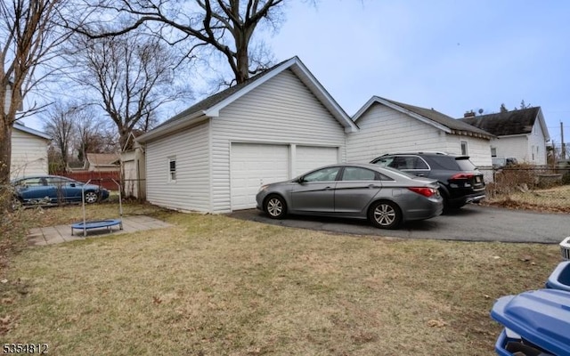view of side of property featuring a lawn, an attached garage, fence, and aphalt driveway