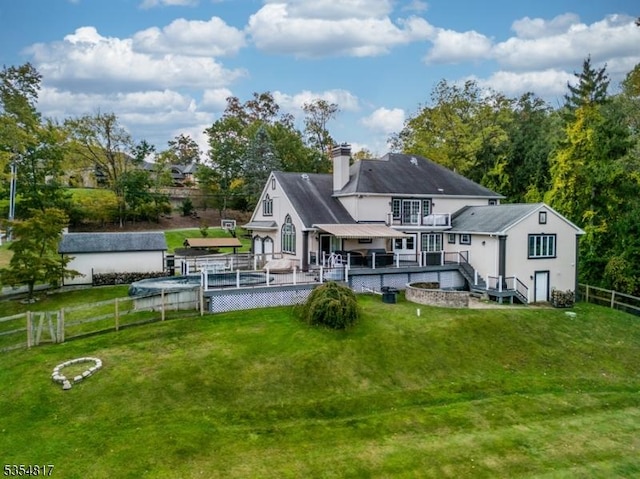 back of house featuring a fenced backyard, a chimney, a lawn, and a deck