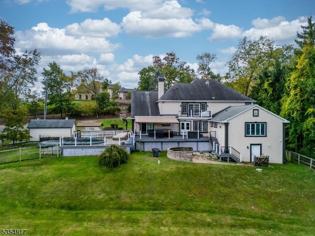 back of property with fence, a wooden deck, a chimney, and a yard