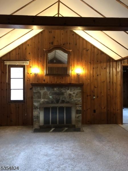 218 Wawayanda Rd, Vernon Twp, NJ 07422 - unfurnished living room with carpet flooring, wooden walls, vaulted ceiling with beams, and a fireplace