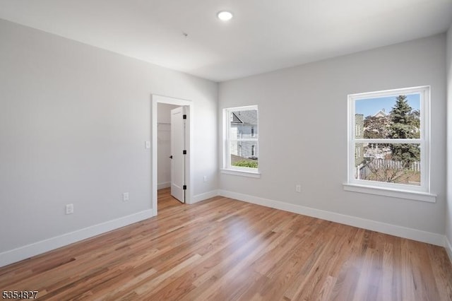 spare room with baseboards, light wood-style flooring, and a wealth of natural light