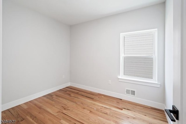 empty room with visible vents, baseboards, and wood finished floors