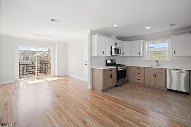 kitchen featuring visible vents, a healthy amount of sunlight, tasteful backsplash, a sink, and appliances with stainless steel finishes