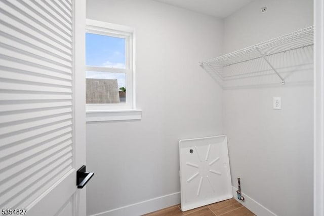 washroom with laundry area, baseboards, and wood finished floors