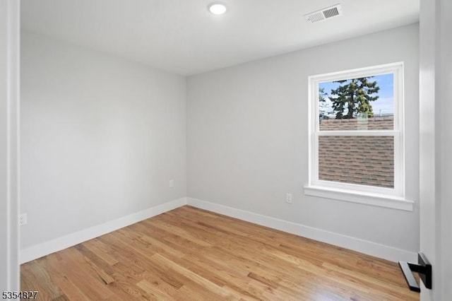 spare room with baseboards, visible vents, and light wood finished floors