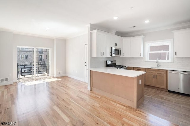 kitchen with crown molding, a sink, light countertops, stainless steel appliances, and tasteful backsplash