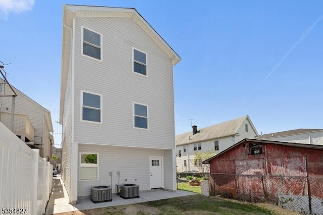 back of property with fence, a patio, and central AC