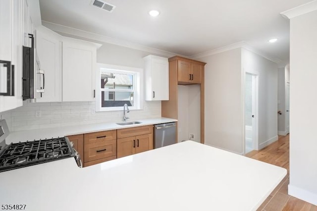 kitchen with visible vents, ornamental molding, tasteful backsplash, a sink, and stainless steel appliances