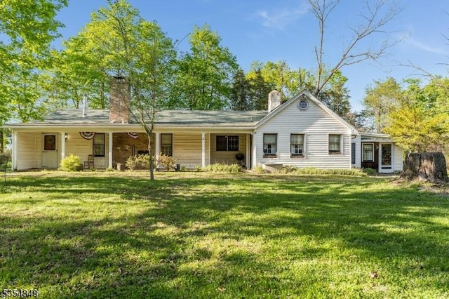 back of house featuring a lawn, a chimney, and a porch