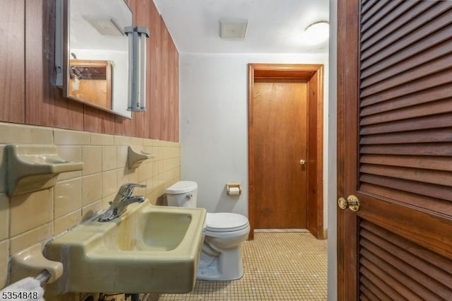 half bath with tile patterned flooring, a sink, and toilet