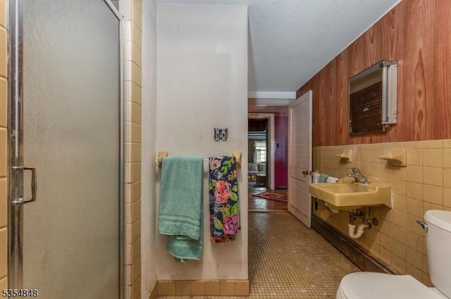 bathroom featuring toilet, tile walls, tile patterned floors, a shower stall, and a sink