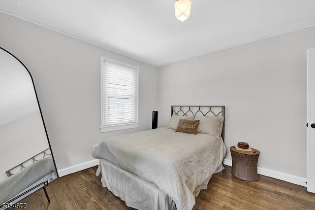 bedroom featuring wood finished floors, baseboards, and ornamental molding
