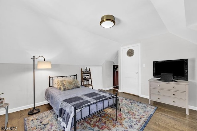 bedroom featuring wood finished floors, lofted ceiling, and baseboards