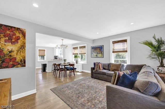living room with wood finished floors, a chandelier, baseboards, and recessed lighting