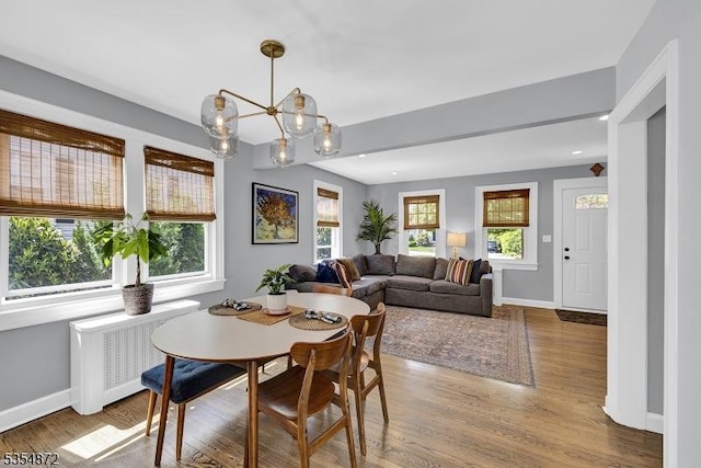 dining area featuring radiator, wood finished floors, baseboards, and a chandelier