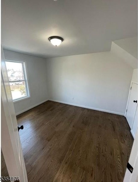 empty room with dark wood-type flooring and baseboards