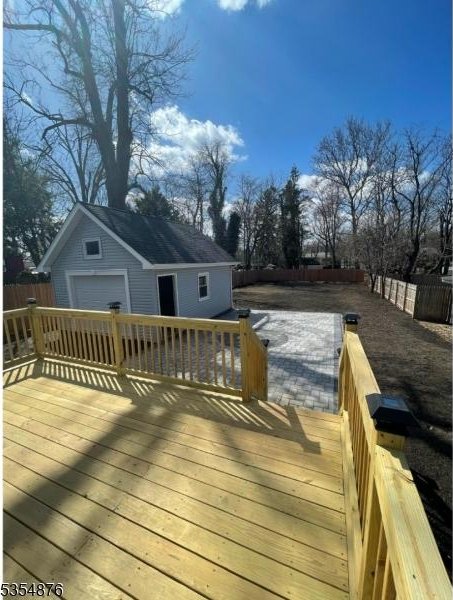 wooden terrace featuring fence, an outdoor structure, and a garage