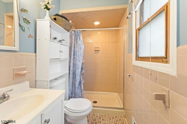 full bath featuring tile walls, a stall shower, tile patterned floors, a wainscoted wall, and toilet