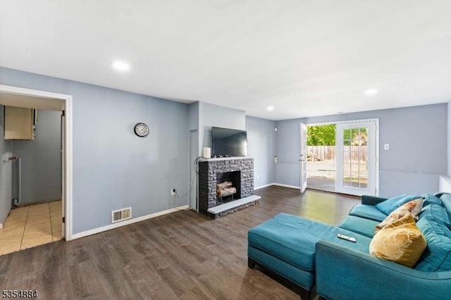 living area featuring a fireplace with raised hearth, recessed lighting, baseboards, wood finished floors, and visible vents