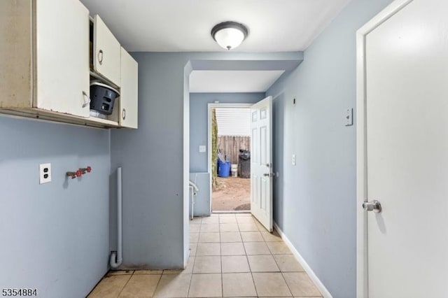 clothes washing area with light tile patterned floors and cabinet space