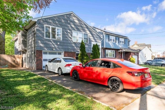 view of front of home with fence, an attached garage, a front lawn, aphalt driveway, and brick siding