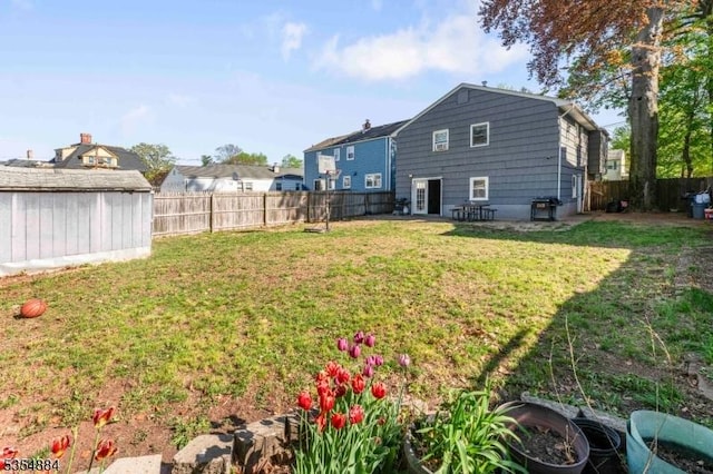 view of yard with a fenced backyard, an outbuilding, and a storage shed