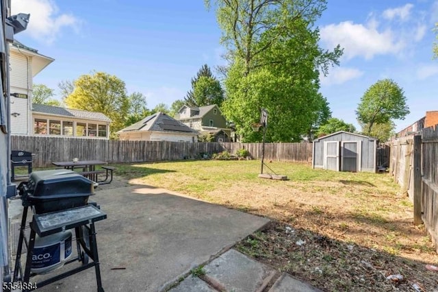 view of yard with a patio, a fenced backyard, an outbuilding, and a storage unit