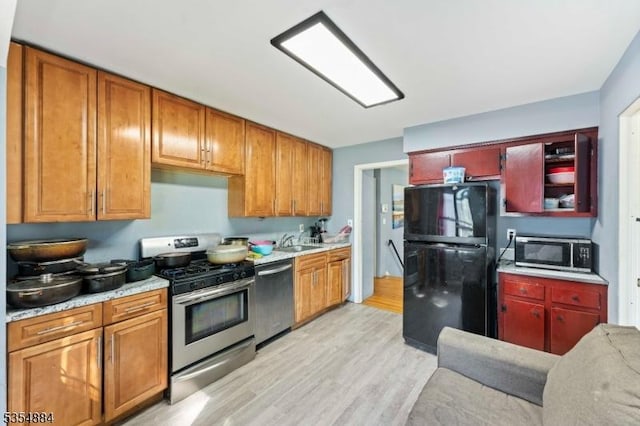 kitchen with a sink, light wood finished floors, appliances with stainless steel finishes, and light countertops