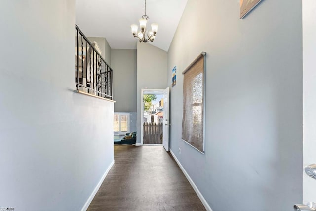 hall featuring baseboards, wood finished floors, a chandelier, and high vaulted ceiling