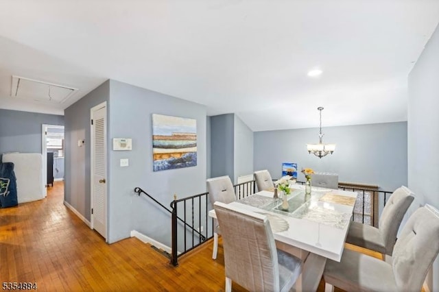dining area with wood-type flooring, attic access, baseboards, and an inviting chandelier