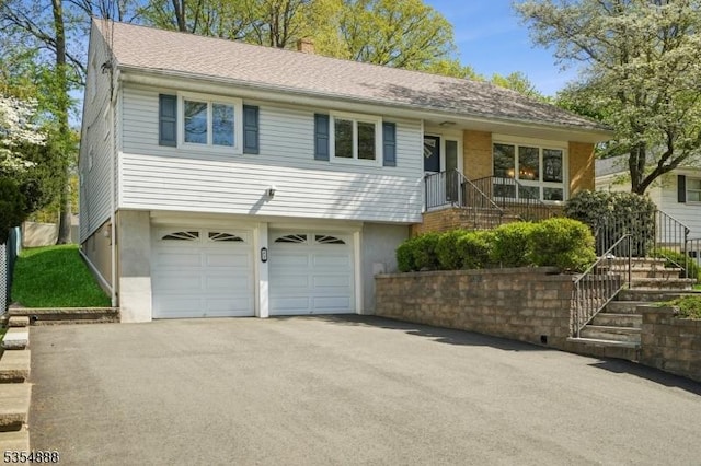 view of front of property featuring stairs, an attached garage, driveway, and a chimney
