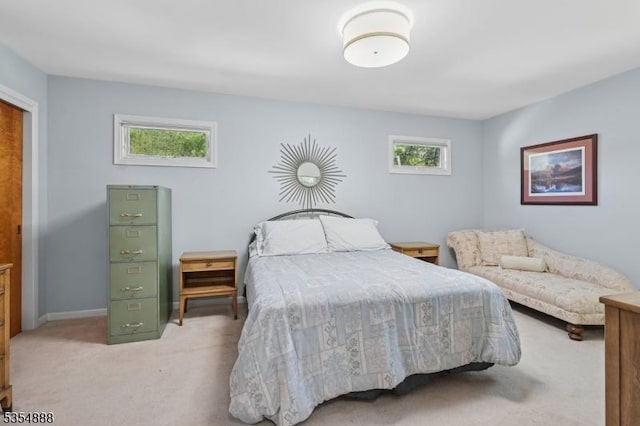 bedroom featuring baseboards, light carpet, and multiple windows