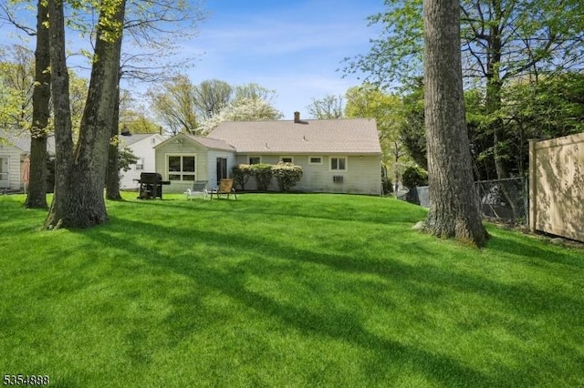 back of house with a yard, fence, and a chimney