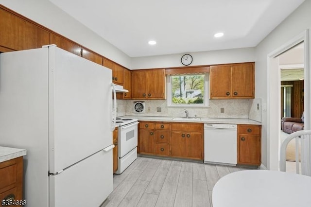 kitchen with white appliances, brown cabinetry, and light countertops