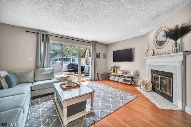 living room with a fireplace, a textured ceiling, and wood finished floors