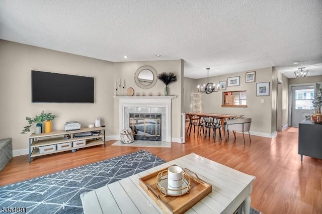 living area with an inviting chandelier, a textured ceiling, recessed lighting, wood finished floors, and a tile fireplace