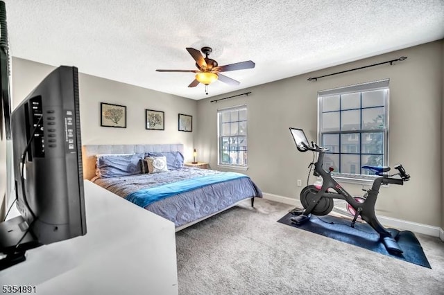 carpeted bedroom with a textured ceiling, baseboards, and ceiling fan