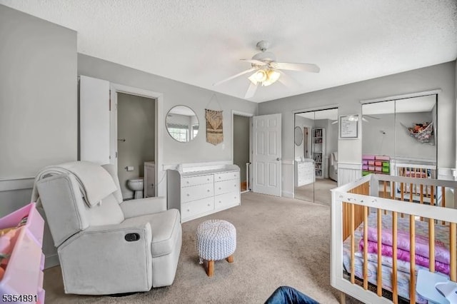 bedroom featuring carpet flooring, a textured ceiling, a ceiling fan, and two closets