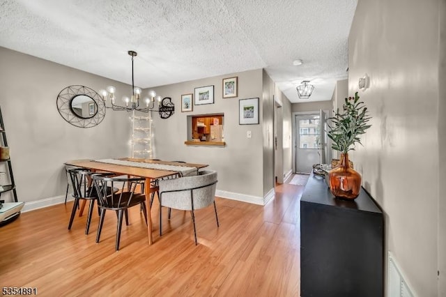 dining room featuring a chandelier, a textured ceiling, visible vents, and light wood-type flooring
