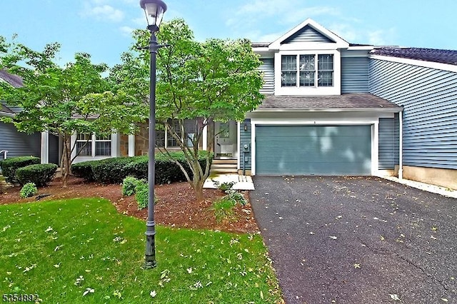 view of front facade with a garage, a front lawn, driveway, and a shingled roof